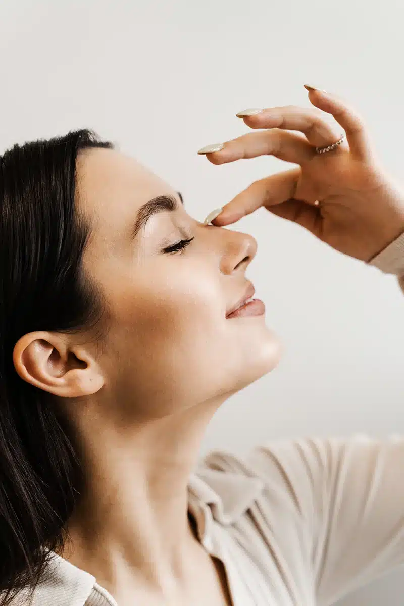 girl touches her nose and smiles after rhinoplasty nose reshaping surgery